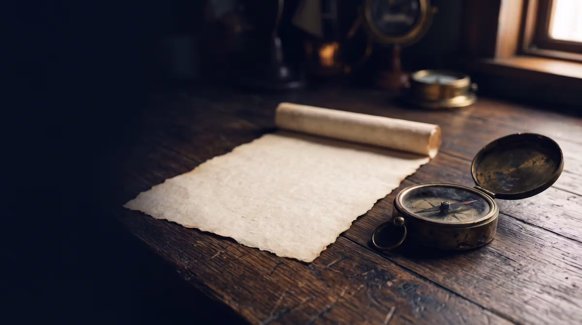 An unrolled scroll and a brass compass on a dark table